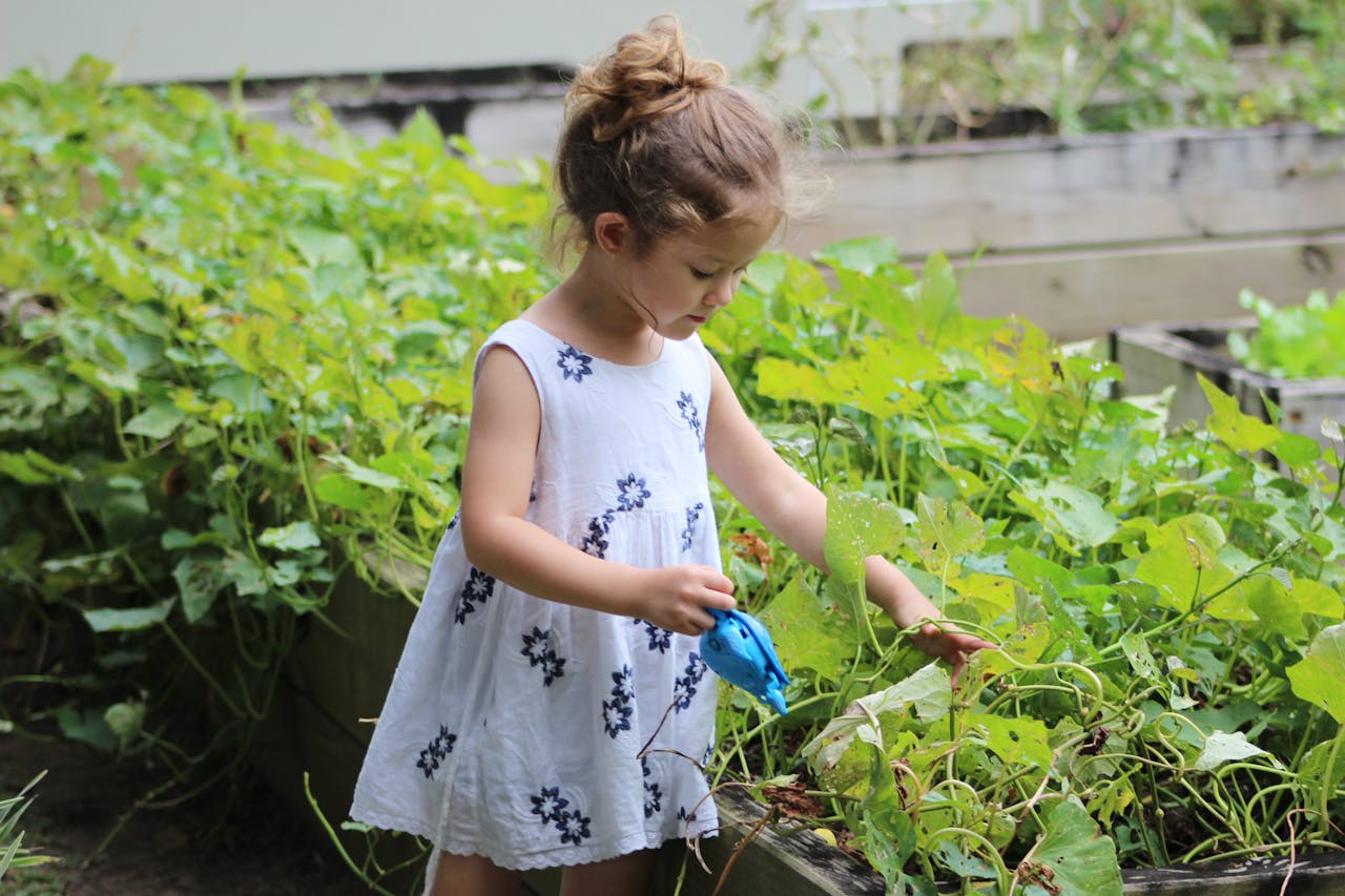 gallery-01 A young girl tending to plants in a summer garden, capturing joy and nature.