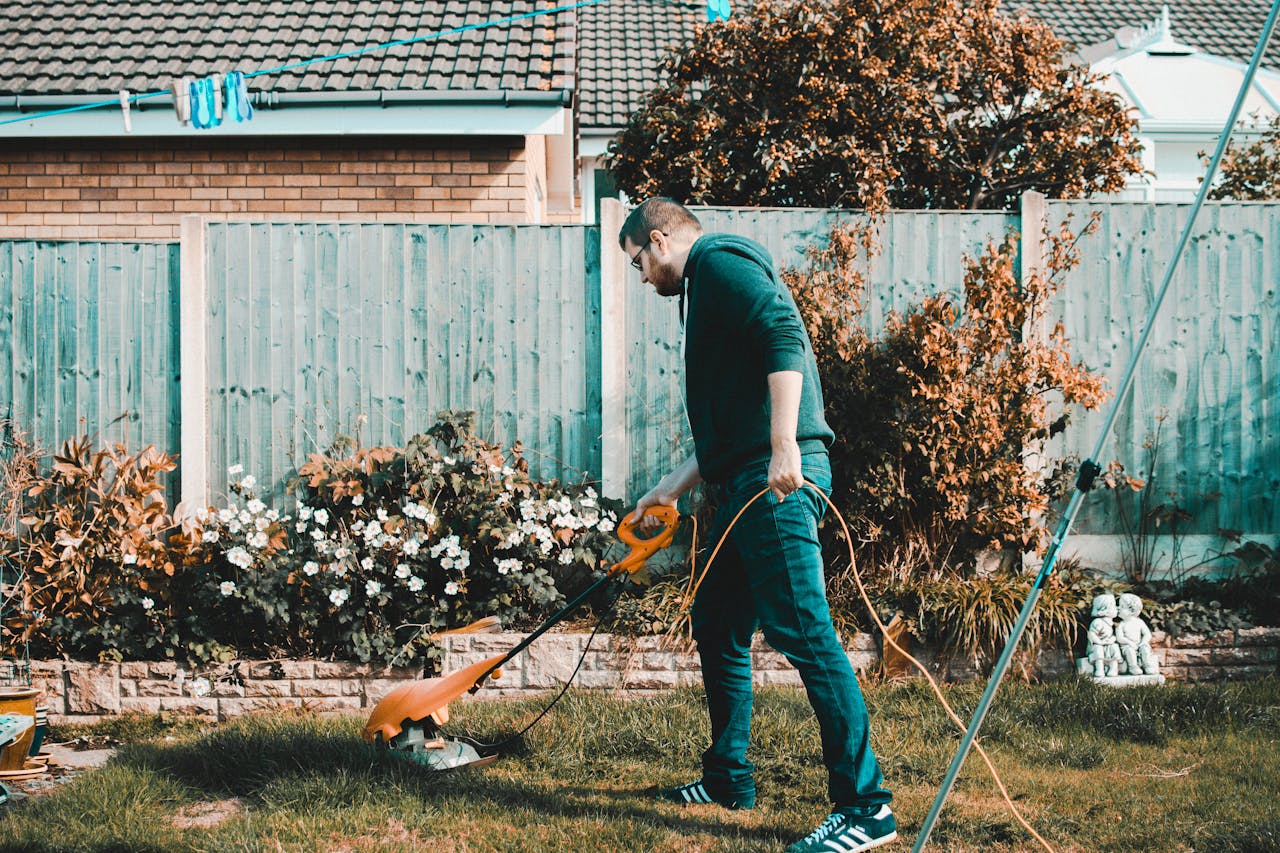 about-img-01 A man using an electric mower in a garden on a sunny day, capturing outdoor chores and gardening vibes.